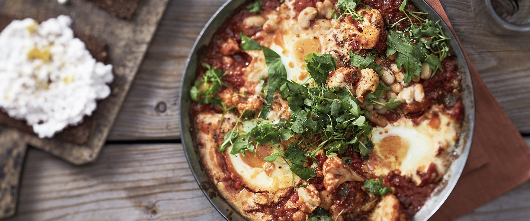 Shakshuka mit Blumenkohl, weißen Bohnen, Ei und Hüttenkäse-Röstbrot